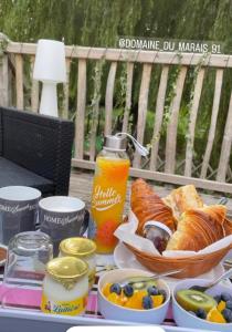 a table with a tray of bread and a bowl of fruit at Cabane perchée luxe avec jacuzzi Domaine du Marais Maisse in Maisse