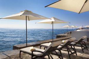 a group of chairs and umbrellas next to the ocean at Hotel Lungomare Opatija - by Liburnia Hotels & Villas in Opatija