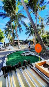 Ein Mann, der auf einem künstlichen Golfplatz mit Palmen Golf spielt in der Unterkunft Neena S Hostel in Ban Nua