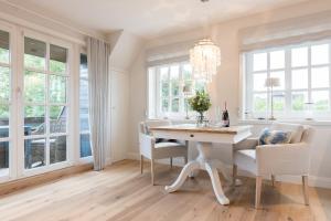 a dining room with a table and chairs and windows at Wattjuwel ehem Wattperle in Munkmarsch