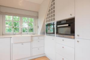 a white kitchen with white cabinets and a window at Wattjuwel ehem Wattperle in Munkmarsch