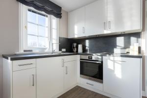 a white kitchen with white cabinets and a window at Windlicht in Munkmarsch +15 photos