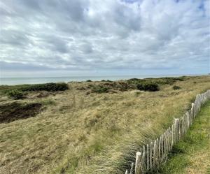a fence in a field with the ocean in the background at Hafen27List - Meeresrauschen - Haus 4 in List