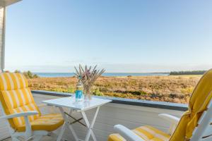 a table and chairs on a balcony with a view of the ocean at Wattblick in Munkmarsch