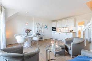 a living room with a table and chairs and a kitchen at Wattblick in Munkmarsch