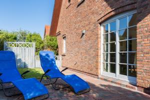 two blue chairs sitting outside of a brick building at Heide Hues in Munkmarsch