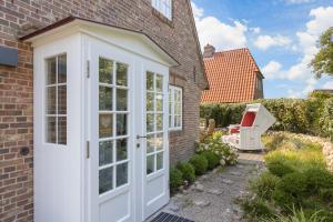 a white door on a brick house with a patio at Hues Uep Klef in Morsum