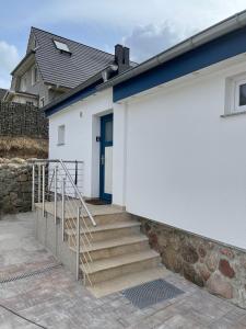 - un bâtiment blanc avec une porte bleue et des escaliers dans l'établissement Klein aber Fein mitten in Binz, à Binz