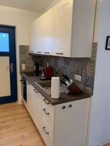 uma cozinha com armários brancos e um lavatório em Klein aber Fein mitten in Binz em Binz