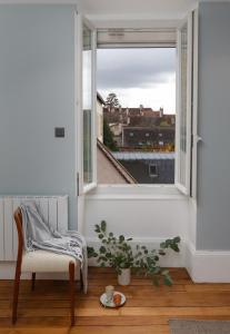 Cette chambre blanche dispose d'une chaise et d'une fenêtre. dans l'établissement Maison Lùisa, à Autun