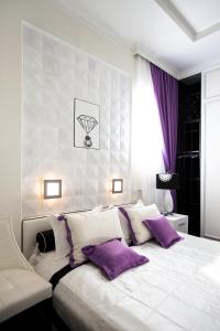 a bedroom with a large white bed with purple pillows at Mirax Boutique Hotel in Kharkiv