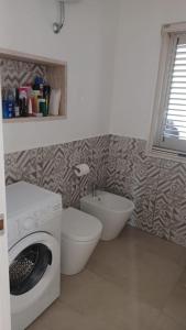 un bagno con lavatrice e WC di Casa Vacanza Villa Stefy - Salento a Torre Chianca Altre 23 foto