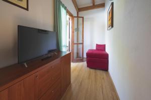 sala de estar con TV de pantalla plana y taburete rojo en Heliopolis Camping & Village, en Pineto