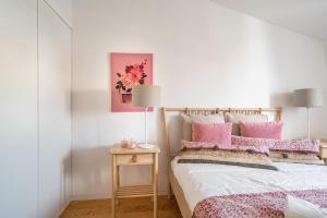 Akicity Anjos Light في لشبونة: غرفة نوم مع سرير مع وسائد وردية وطاولة