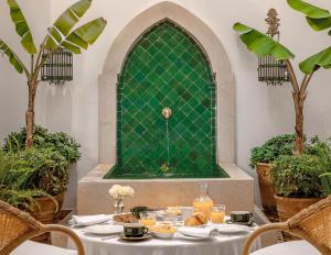 un tavolo con piatti di cibo sopra davanti a una parete verde di Riad L'Hôtel Marrakech a Marrakech