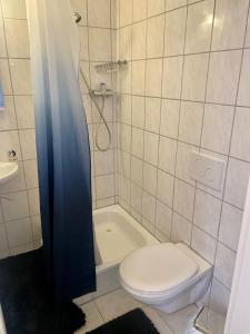 a bathroom with a toilet and a tub and a sink at Le MONOT Residence in Basel