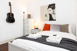 a bedroom with a bed with towels and a guitar at Bright & Cozy 1 BDR Apt wCharming Private Terrace in London