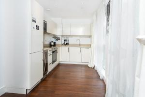 a kitchen with white cabinets and a wooden floor at Bright & Cozy 1 BDR Apt wCharming Private Terrace in London