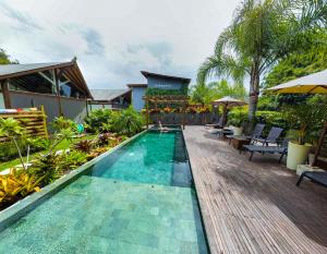 a swimming pool in a resort with a wooden deck at Village do Luz in Barra de Ibiraquera