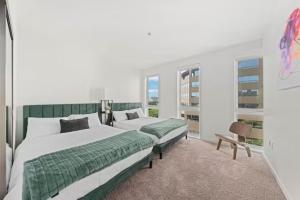 a bedroom with two beds and a chair and windows at Downtown Santa Monica Top Floor Ocean View 2BR/2BA in Los Angeles