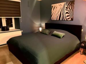 a bedroom with a bed with a zebra painting on the wall at Chez Koulla et Romu in Durbuy
