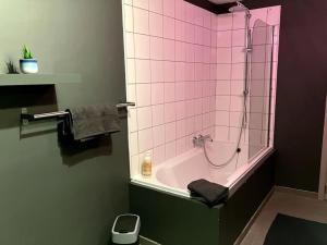 een badkamer met een roze betegelde douche en een bad bij Chez Koulla et Romu in Durbuy