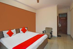 una camera da letto con un letto con cuscini rossi e una sedia di OYO Flagship Mohan Residency a Indirapuram
