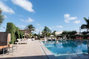 a large swimming pool with lounge chairs and umbrellas at Mirage Studios in Malia