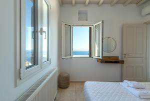 a bedroom with white walls and windows and a bed at La Chapelle Est in Agios Romanos