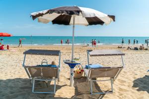 twee stoelen onder een parasol op een strand bij Hotel Parigi in Bibione