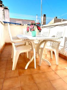 a white table and chairs on a balcony with flowers at Barrio San Miguel Más que apartamentos in Murcia