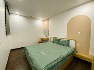 een kleine slaapkamer met een bed met een groene deken bij Căn Hộ Cao Cấp 2 Ngủ Grand Tower in Hai Phong