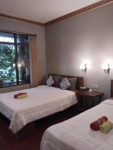 a hotel room with two beds and a window at Dewa Bungalows in Ubud