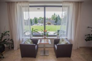 een woonkamer met 2 stoelen en een tafel en een groot raam bij Luxury villa near Prague with pool and tennis court in Čestlice