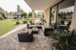 une terrasse avec des canapés et des chaises dans une maison dans l'établissement Luxury villa near Prague with pool and tennis court, à Čestlice