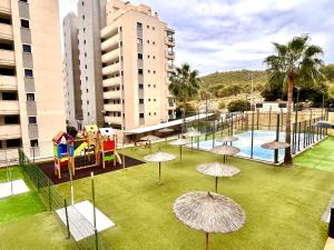 a park with a playground with umbrellas on the grass at Alkadir Home in Villajoyosa
