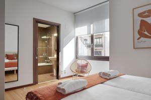 een slaapkamer met een bed, een stoel en een raam bij Eiffel - The Rentals Collection in San Sebastian
