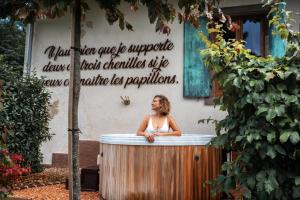 une femme debout dans une baignoire devant un bâtiment dans l'établissement Le Grand Petit Prince - Domaine de Charme - Jacuzzis privatifs, à Guebwiller