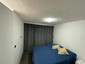 Un dormitorio con una cama azul en una habitación blanca. en Ñuñoa, Bello departamento, La mejor ubicacion, en Santiago 17 fotos más