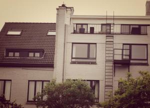 a tall white building with a fire ladder on it at B&B Lieven Bauwens in Ghent