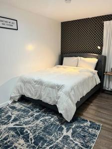 a bedroom with a large bed with white sheets and a rug at Cozy 2BED 6min EWR NYC DTWN in Newark