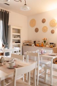 uma sala de jantar com mesas brancas e cadeiras brancas em Palazzo De Luca by Apulia Hospitality em Fasano