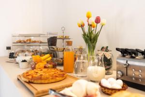 a table with a pizza on a cutting board and flowers at Palazzo De Luca by Apulia Hospitality in Fasano