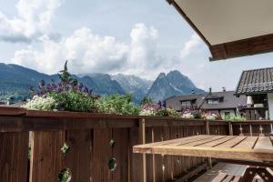 une terrasse en bois avec une table en bois et des fleurs dans l'établissement Gästehaus Quirin, à Garmisch-Partenkirchen