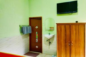 a bathroom with a sink and a television on the wall at Hotel Antik in Soreang