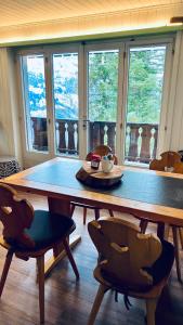 comedor con mesa, sillas y ventanas en Chalet Tännli - CharmingStay, en Flumserberg