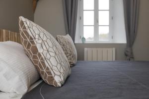 a bed with four pillows on it with a window at L'annexe du Moulin Renaudiots in Autun