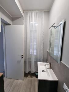 a bathroom with a sink and a mirror and a door at Cà Fiamma in Casale Monferrato