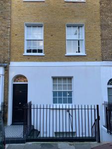 ein weißes Gebäude mit einer schwarzen Tür und zwei Fenstern in der Unterkunft Sale Place Serviced Apartments by Concept Apartments in London