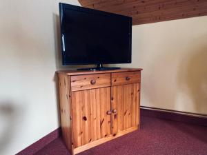 telewizor z płaskim ekranem na drewnianej szafce w obiekcie Myslivna Harrachov w mieście Harrachov